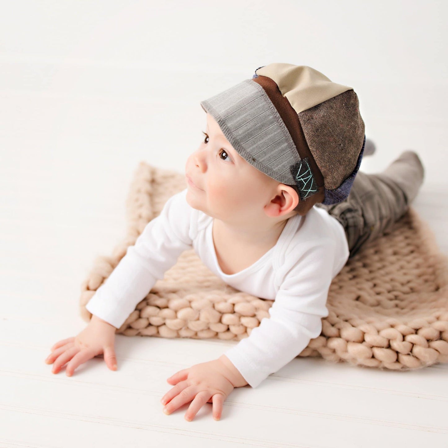 Baby wearing a patchwork JAX Upcycled hat on a white background