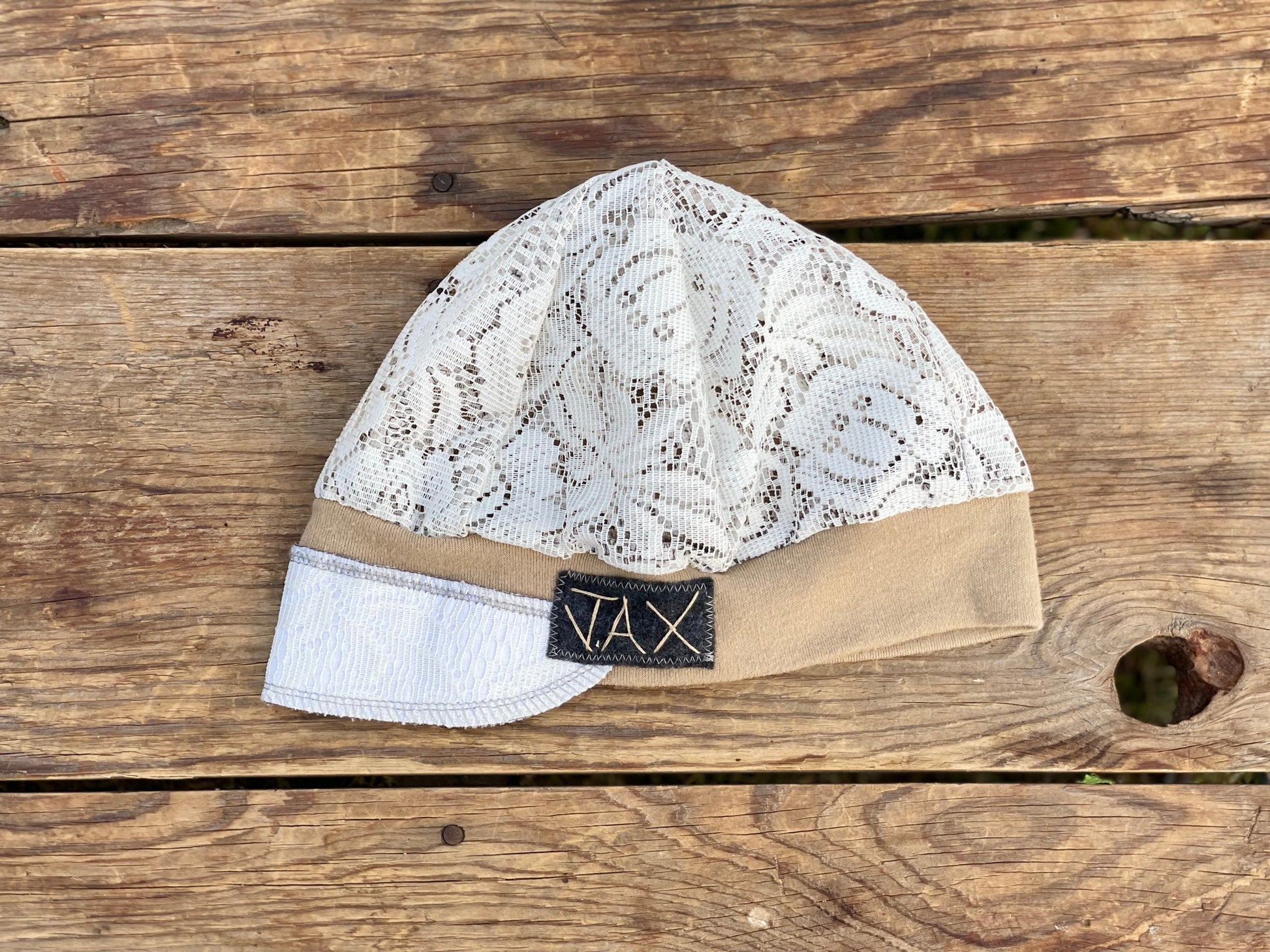 Upcycled lace curtain made into a hat laying on wooden table