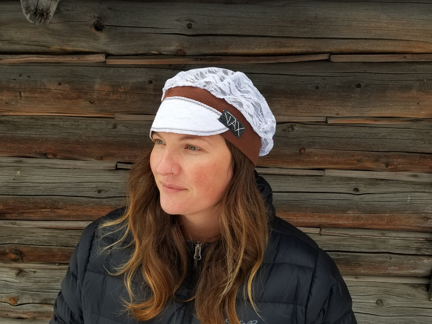 Lady with lace hat with decorative band against log cabin