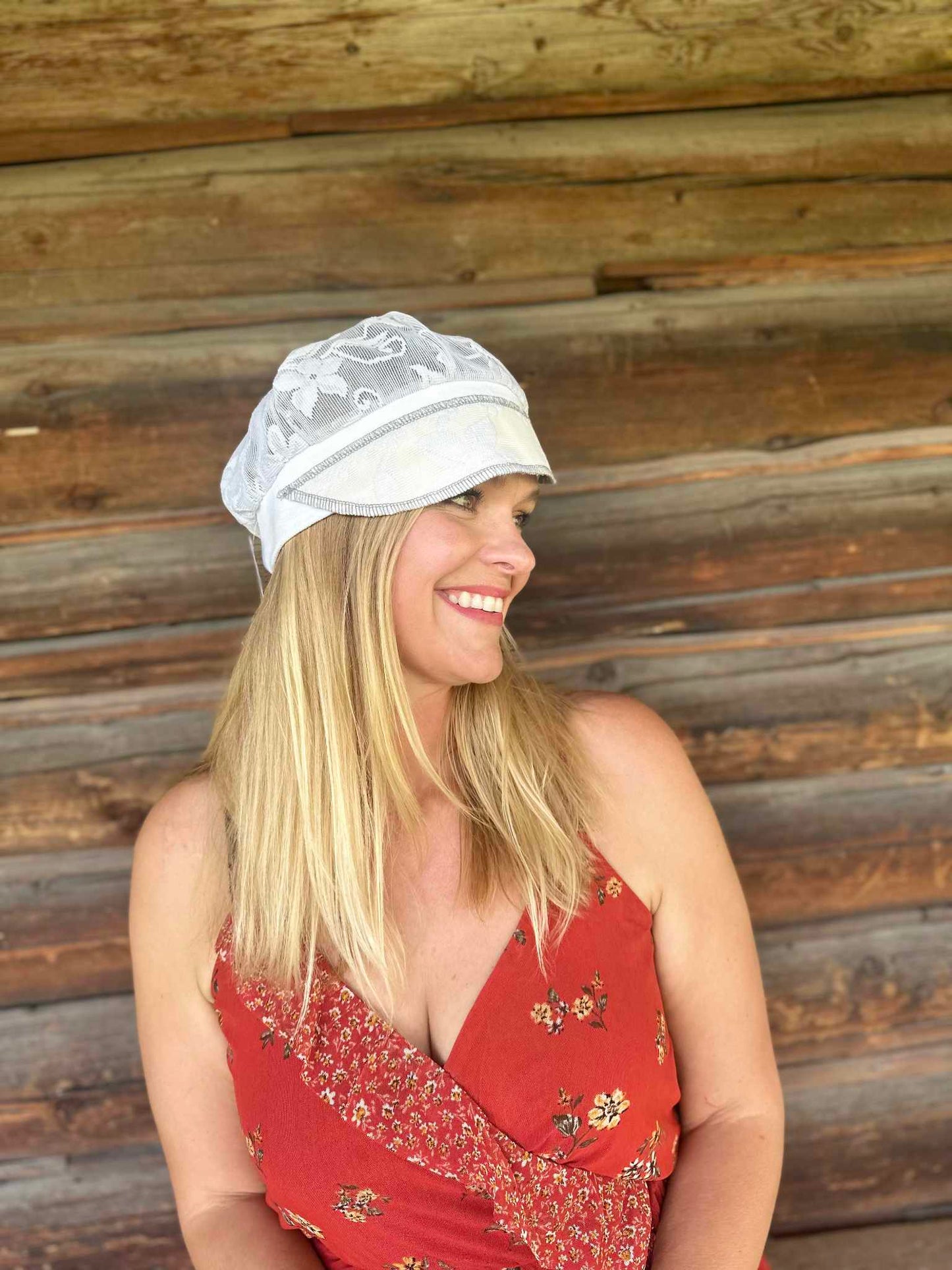 Lady with lace hat with decorative band against log cabin