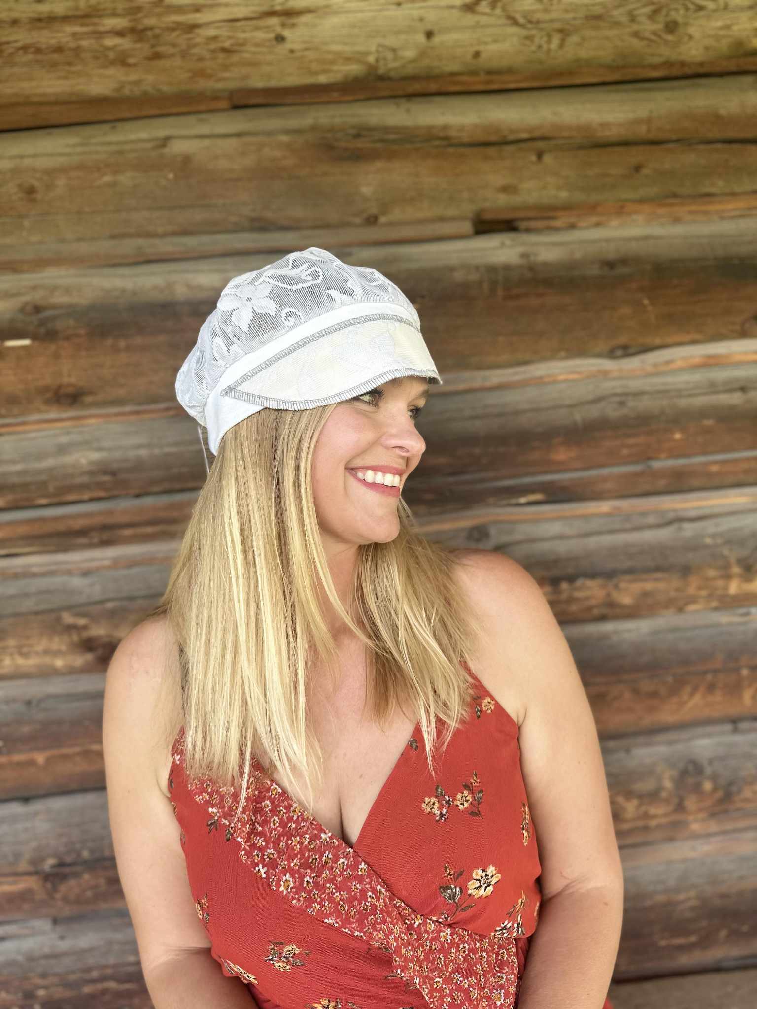 Lady with lace hat with decorative band against log cabin
