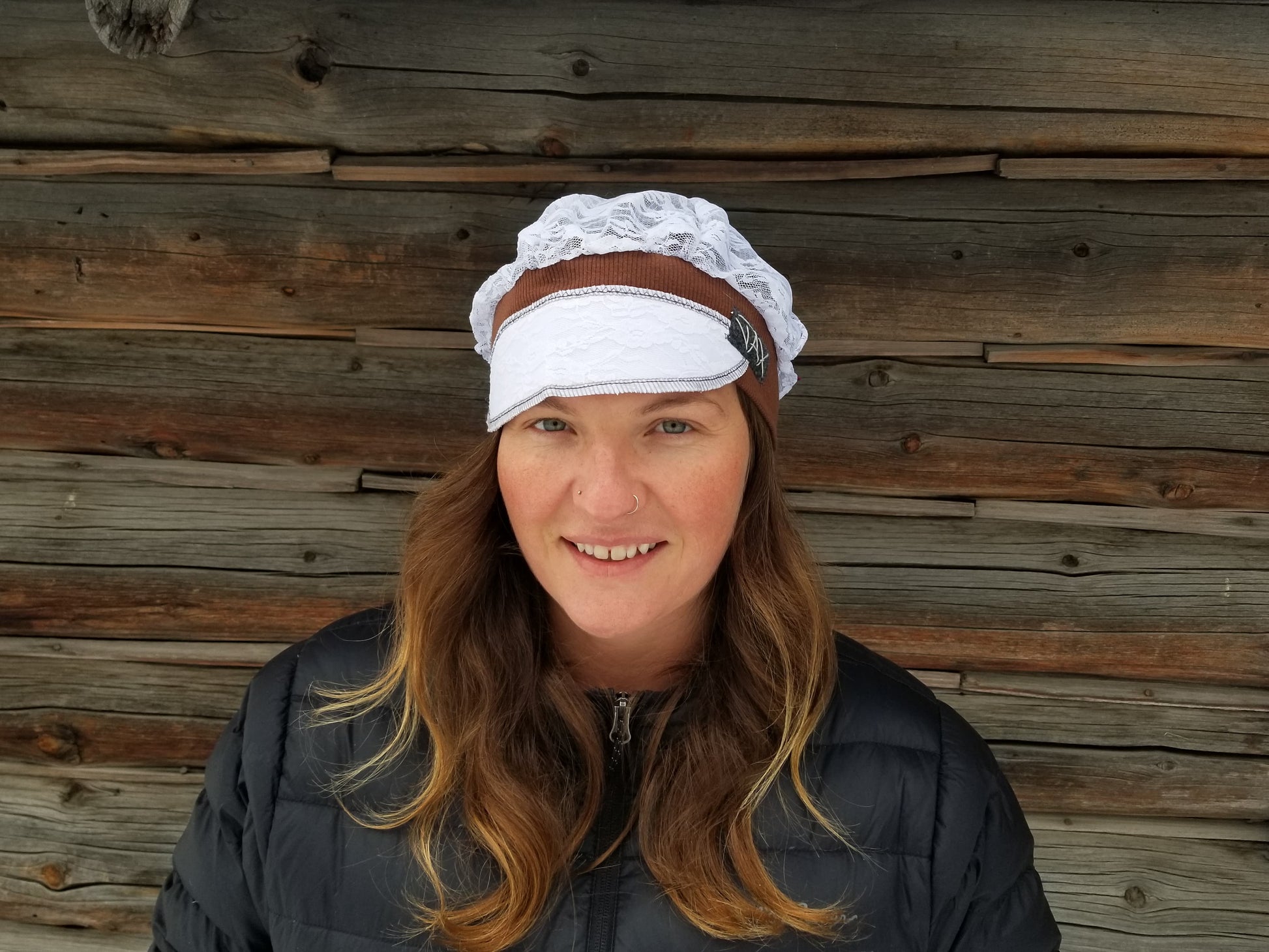 Lady with lace hat with decorative band against log cabin