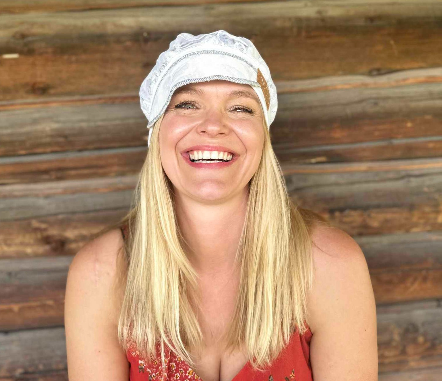 Laughing lady with lace hat against log cabin