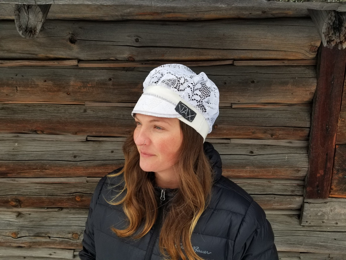 Lady with lace hat with decorative band against log cabin