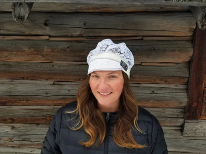Lady with lace hat with decorative band against log cabin